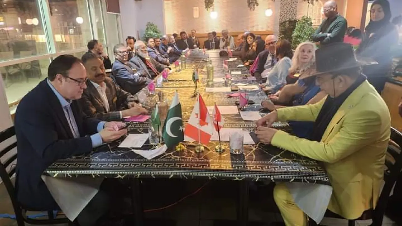 Guests along a long dinner table set with small Pakistani and Canadian flags